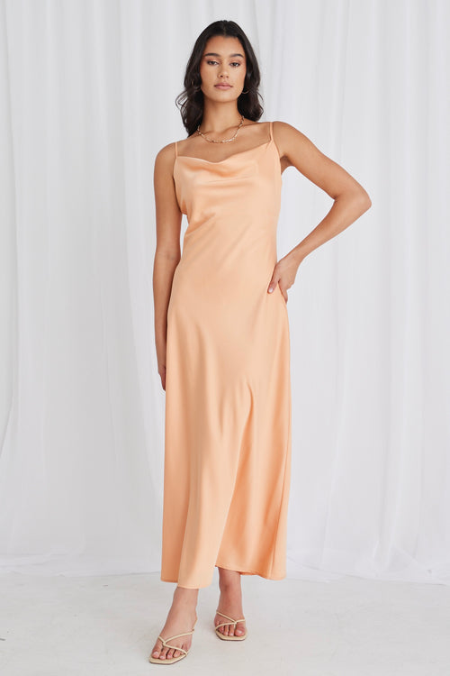 Model posing in orange satin maxi dress and heels