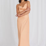 Model posing in orange satin maxi dress and heels