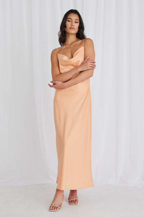 Model posing in orange satin maxi dress and heels