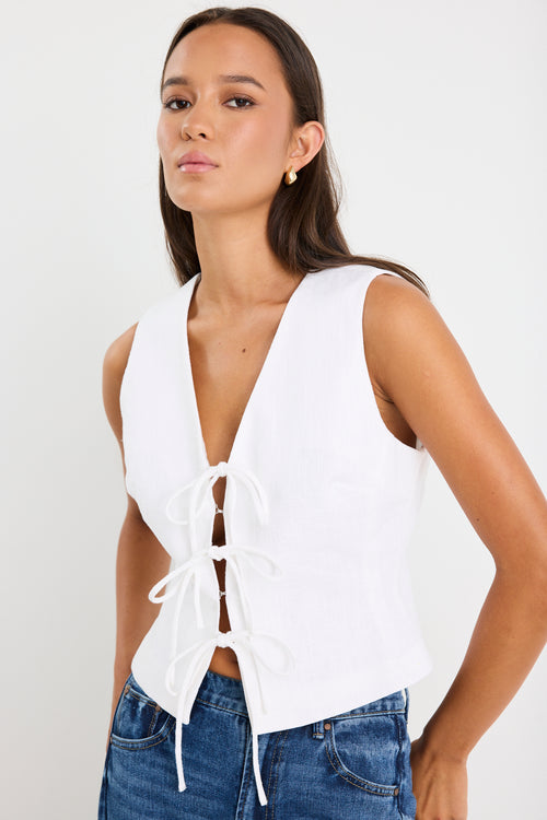 White sleeveless vest top with tie-up front detail, made from structured ramie, styled with high-waisted blue jeans.