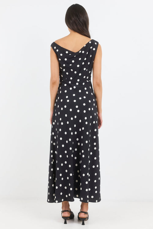 Woman wearing a black dress with white polka dots on a white background