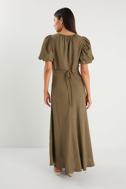 Woman wearing a long olive green dress with puff sleeves on a white background