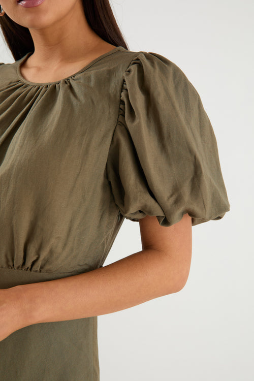 Green blouse with puff sleeves worn by a person on a white background