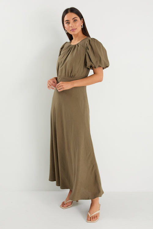 Woman wearing a green dress with puff sleeves on a white background
