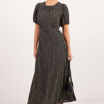 A woman modeling a black and beige animal print maxi dress with puff sleeves, sunglasses, and black sandals against a plain white studio background.