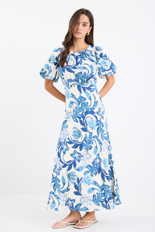 A short-sleeve floral dress with puff sleeves and a bias-cut design. The dress features a blue floral print on a cream background and is fully lined for comfort.