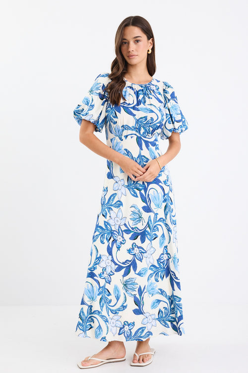 A short-sleeve floral dress with puff sleeves and a bias-cut design. The dress features a blue floral print on a cream background and is fully lined for comfort.