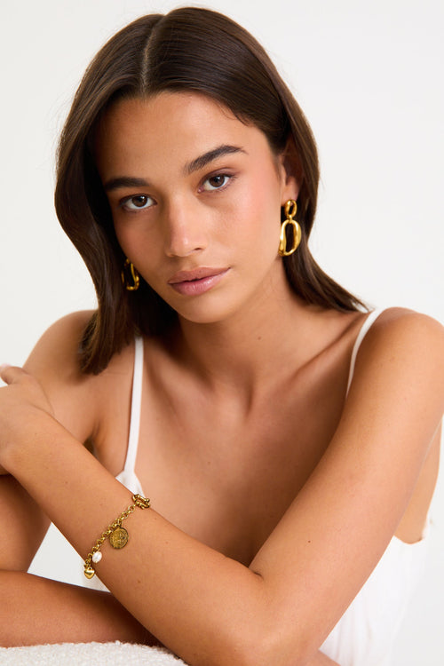 Woman wearing gold jewelry against a white background