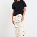 Woman wearing a black t-shirt and white polka dot skirt on a white background