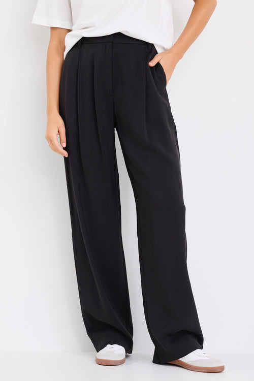 model wears black high waisted pants with a white tee