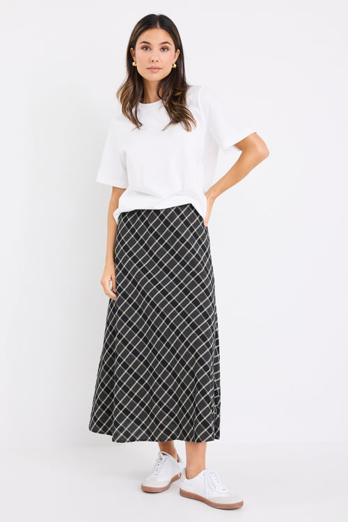 the model wears a black and white check midi skirt with a white t-shirt