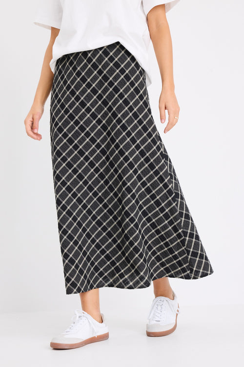 the model wears a black and white check midi skirt with a white t-shirt