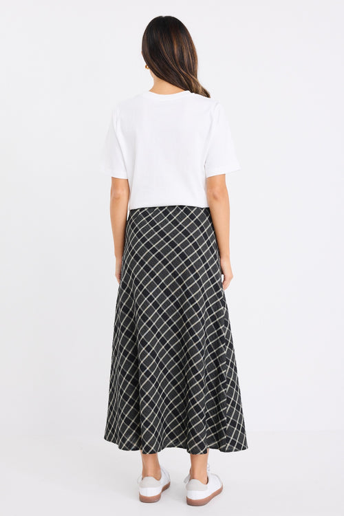 the model wears a black and white check midi skirt with a white t-shirt