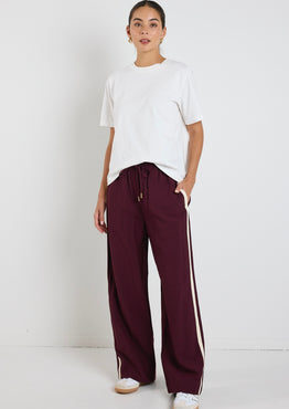 model wears white tee with dark red pants with a white side stripe