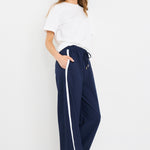 Woman wearing high-rise plain navy wide-leg pants with an elastic waistband and drawstring tie, styled with white sneakers and a white tee.