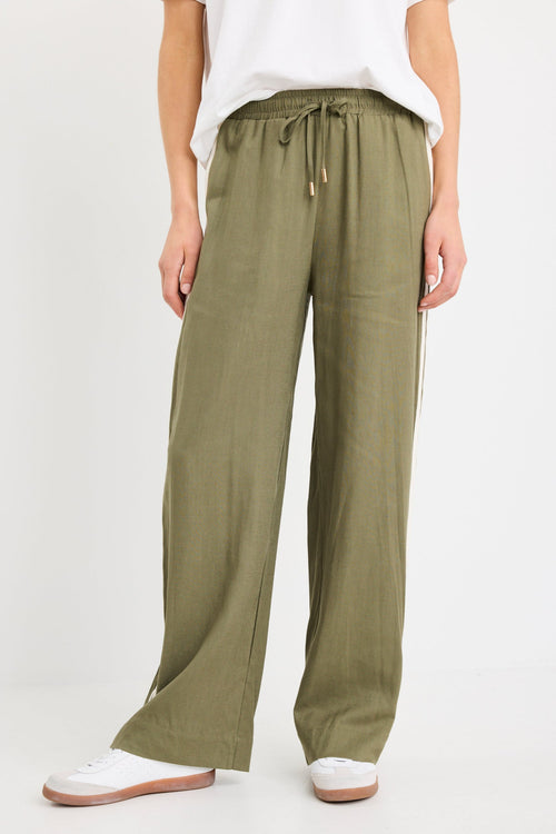 Woman wearing khaki wide-leg drawstring pants with an elastic waist, featuring a relaxed fit and side stripe detail, styled with a plain white tee and white sneakers.