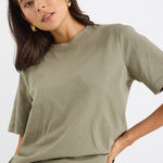 model wears a green khaki t-shirt with light blue jeans