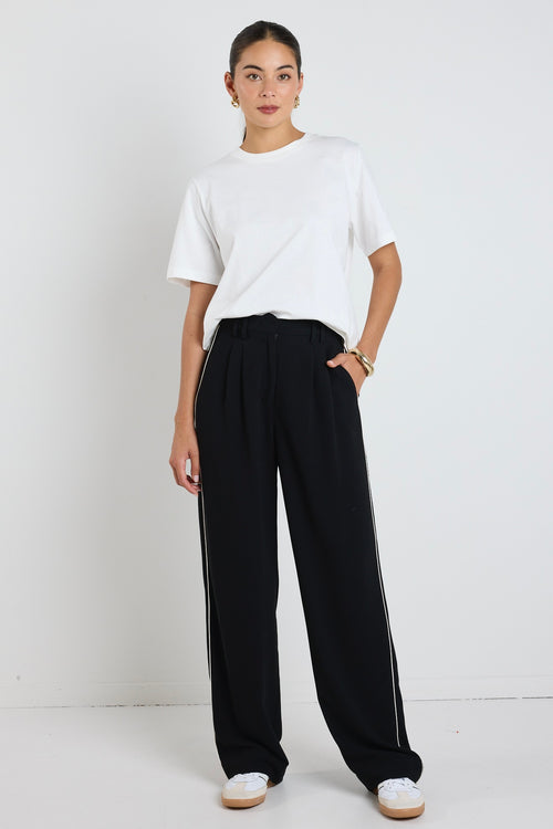 model wears white cotton tee and black pants with a white stripe