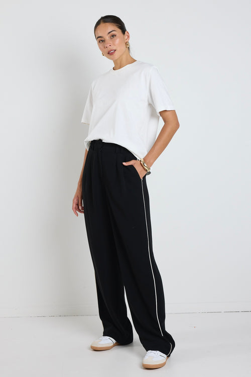 model wears white cotton tee and black pants with a white stripe