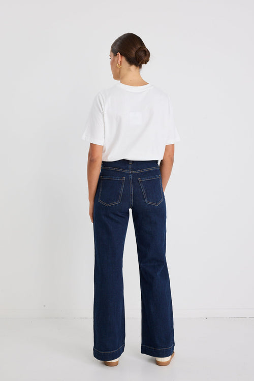 Person wearing a white shirt and dark blue jeans on a white background