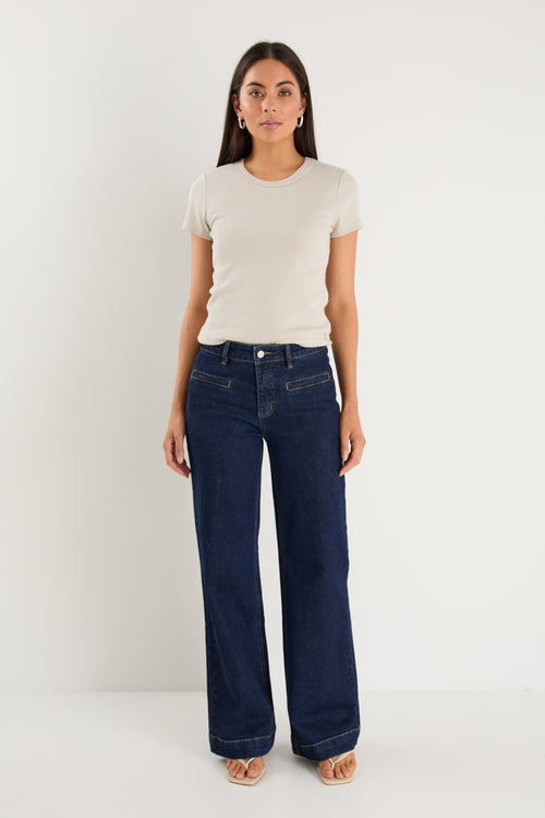 model wearing dark denim jean and white top 