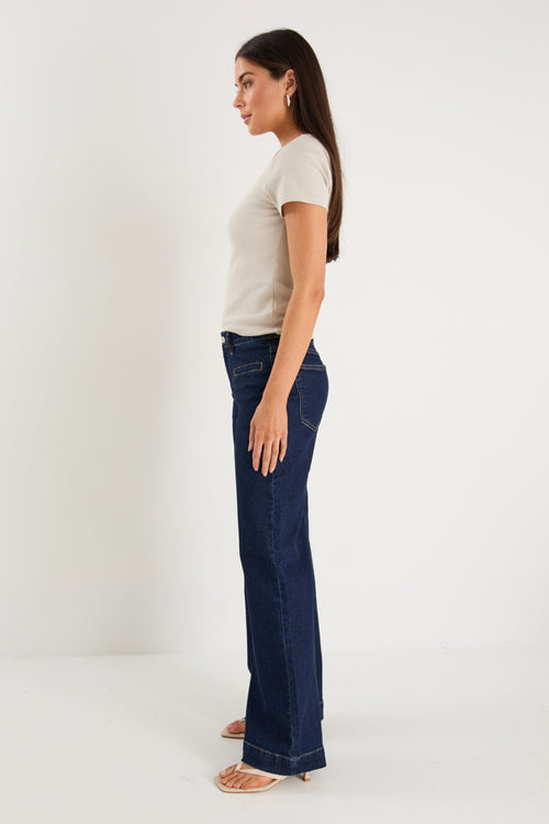 model wearing dark denim jean and white top 
