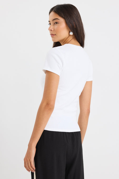 Model wears white stretch knit top with black pants.