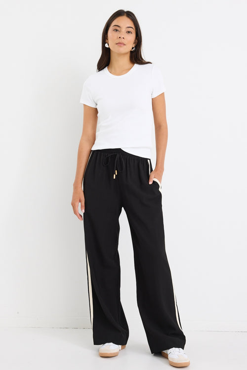 Model wears white stretch knit top with black pants.