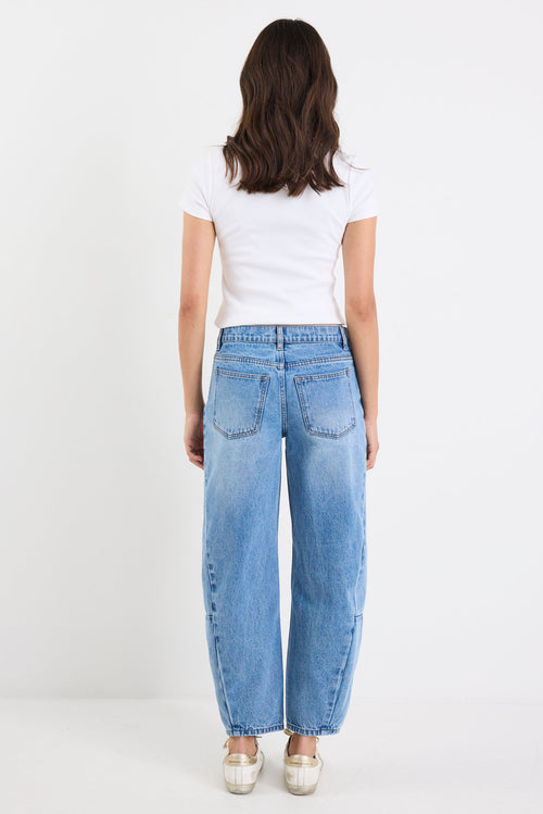 Person wearing light blue jeans and a white shirt on a white background