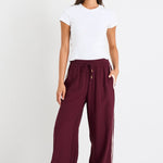 Woman wears a burgundy pant and white top