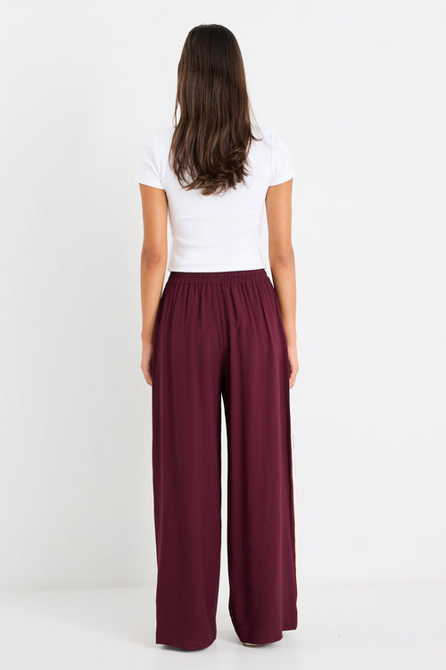 Woman wears a burgundy pant and white top