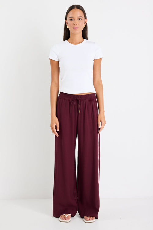 Woman wears a burgundy pant and white top