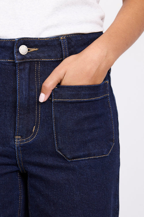 Navy blue jeans worn by a person on a white background