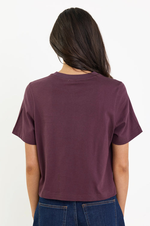 Person wearing a maroon t-shirt and blue jeans on a white background