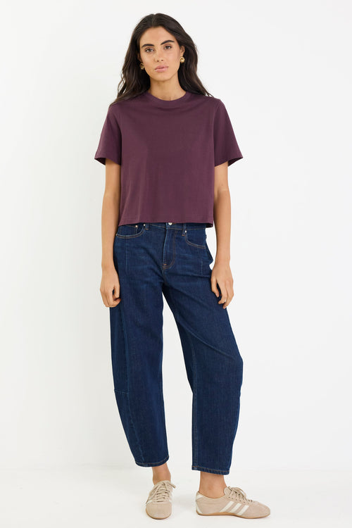 Woman wearing a purple t-shirt and blue jeans on a white background