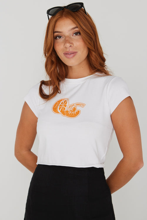 model wearing white crop top tee with an orange on the front and a black skirt