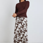 Model wears brown pattern maxi skirt with a tie waist and a long sleeve brown top. 