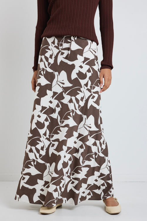 Model wears brown pattern maxi skirt with a tie waist and a long sleeve brown top. 