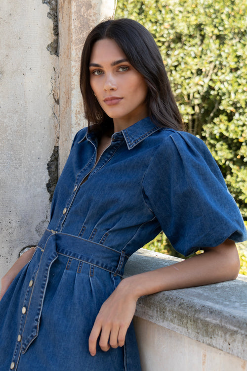 model wears a dark blue denim mini dress