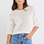 model wears a white knit t-shirt and a light blue jean