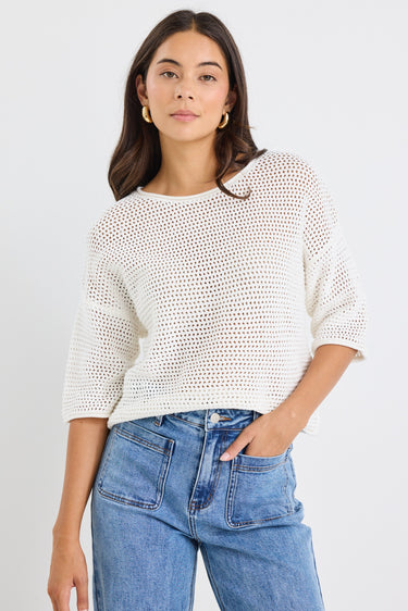 model wears a white knit t-shirt and a light blue jean