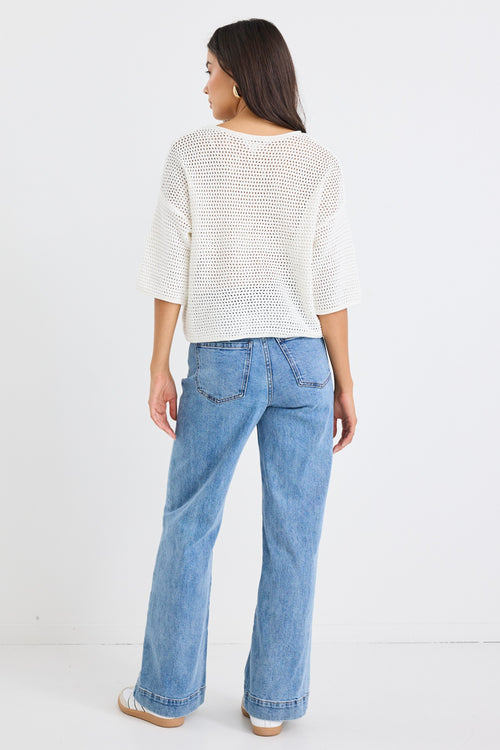 model wears a white knit t-shirt and a light blue jean