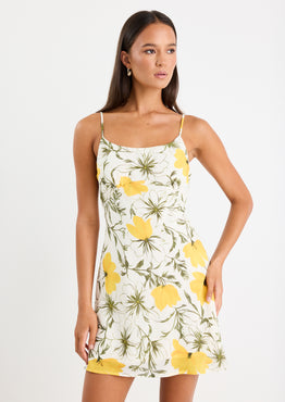 Mini floral bias dress with adjustable straps and a soft, floaty fit, styled with heels and delicate accessories.