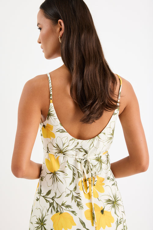 Mini floral bias dress with adjustable straps and a soft, floaty fit, styled with heels and delicate accessories.