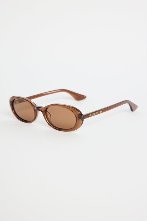 Narrow espresso-brown oval sunglasses with warm brown tinted lenses, photographed against a white background.