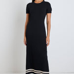 Woman wearing a black rib knit midi dress with short sleeves, styled with white sneakers for a chic and casual look.