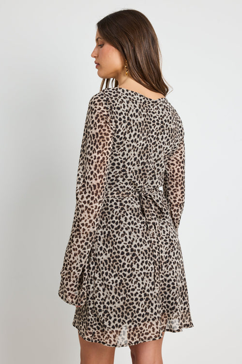 Woman wearing a leopard print mini dress with bell sleeves, styled with sunglasses for a bold and playful look.