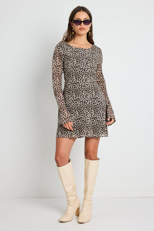 Woman wearing a leopard print mini dress with bell sleeves, styled with sunglasses for a bold and playful look.