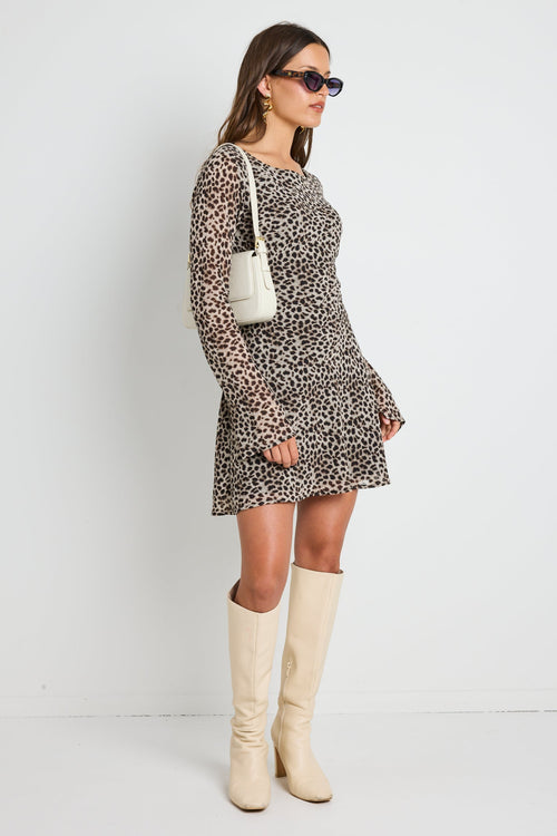 Woman wearing a leopard print mini dress with bell sleeves, styled with sunglasses for a bold and playful look.