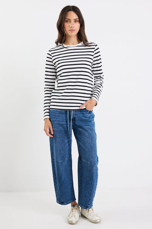Person wearing a black and white striped shirt with blue jeans on a white background
